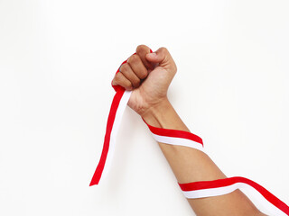 The hands of a man holding a red and white ribbon as a symbol of the Indonesian flag. Isolated on white background. Independence day concept