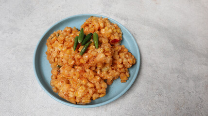 Perkedel Jagung or Bakwan Jagung, corn fritters is Indonesian traditional food. Savory snack made of corn, egg, flour, spring onion, pepper and salt. Served in blue plate on grey background