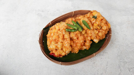 Perkedel Jagung or Bakwan Jagung, corn fritters is Indonesian traditional food. Savory snack made of corn, egg, flour, spring onion, pepper and salt. Served in wicker bamboo plate on grey background