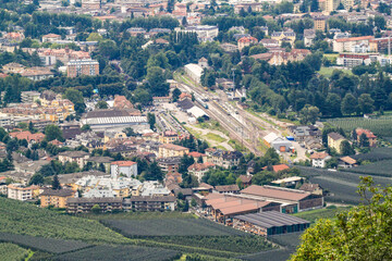 Telephoto view of Merano: low-rise South Tyrolean architecture amid greenery, with trains at the...