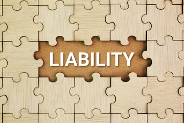 Wooden puzzle with the word Liability. the state of being legally responsible for something. the...