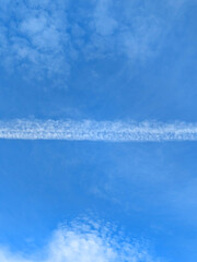 Blue Skies with wispy chemtrail aeroplane lines and fluffy white clouds