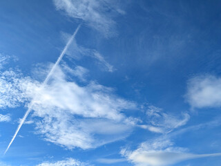 Blue Skies with wispy chemtrail aeroplane lines and fluffy white clouds