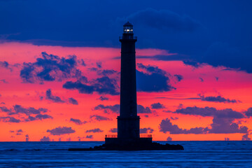 Lighthouse Silhouetted Against Vibrant Sunset in Normandy