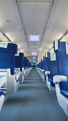 Fototapeta premium A Spacious Train Interior Featuring Rows of Plush Blue Seats with a Clear Perspective Down the Aisle and Modern Lighting Fixtures for a Comfortable Journey Experience