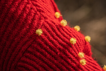 Sweater Texture Yellow Pompoms Red Knitwear: Close-up detail showcasing textured red knit sweater...