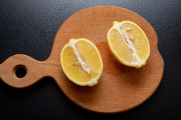 Lemon cut into two halves on a wooden plate close-up. Concept of freshness, cooking and lemonade...