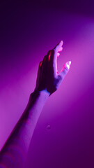 A Stunning Visual Representation of an Outstretched Hand Illuminated by Unique Purple Lighting...