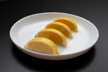 Lemon slices on white plate. Freshness concept, making lemonade with lemon slices. Summer cold...