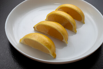 Lemon slices on white plate. Freshness concept, making lemonade with lemon slices. Summer cold...
