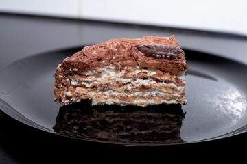 A slice of delicious protein chocolate cake in a cut on a black plate. Dessert on a plate.