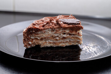 A slice of delicious protein chocolate cake in a cut on a black plate. Dessert on a plate.