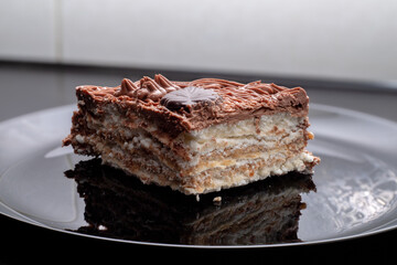 A slice of delicious protein chocolate cake in a cut on a black plate. Dessert on a plate.