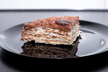 A slice of delicious protein chocolate cake in a cut on a black plate. Dessert on a plate.