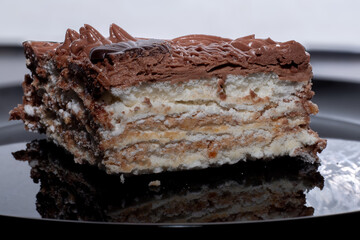 A slice of delicious protein chocolate cake in a cut on a black plate. Dessert on a plate.