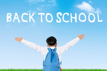 Happy Indonesian Student Raising Hands with “Back to School” Sky Text on Blue Background