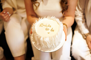 Girl in white holding a cake with an inscription "bride to be"