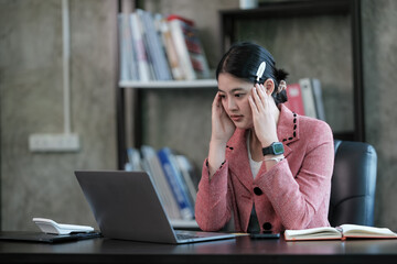 Stressed, exhausted Asian women are noted while working on a laptop, a Tired Asian businesswoman...