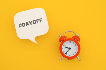 DAY OFF text on real white speech bubble paper cur with red analog alarm clock on yellow background