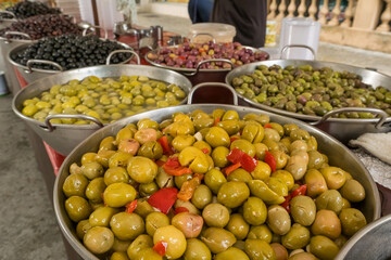 Trays with marinated black green yellow olives at farmers market close-up