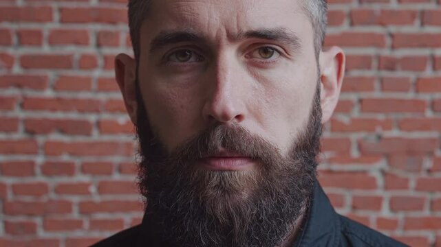 Homme barbu devant mur de briques