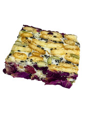 A rectangular piece of a sweet treat, featuring a white base studded with various seeds and crunchy elements on top, and a distinct layer of purple-red dried fruit or petals at the bottom, isolated on
