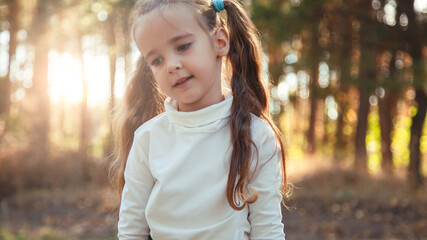 portrait a pretty girl walking in park in nature at sunset