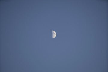 Riga, Latvia 05-09-2024 A Lone Moon Gazes Upward in the Endless Blue Sky