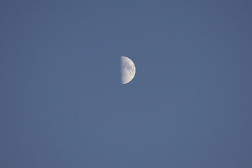 Riga, Latvia 05-09-2024 A Lone Moon Gazes Upward in the Endless Blue Sky
