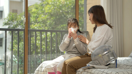 A girl in fencing gear with their mother preparing milk and sports equipment before practicing...