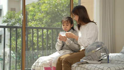 A girl in fencing gear with their mother preparing milk and sports equipment before practicing...