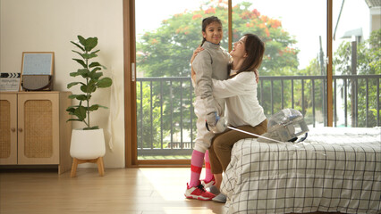 A girl in fencing gear with their mother preparing sports equipment