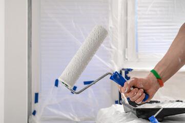 Painter holding a paint roller in his hands, home renovation