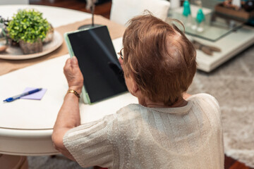 Elderly Woman Engaging with Digital Tablet at Home