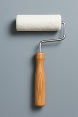 Obraz premium White paint roller with wooden handle on gray wall