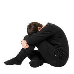 Young man sitting on floor with head down and arms around knees  