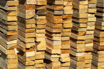  stacked piles of rough-cut lumber with varying shades of natural wood tones.