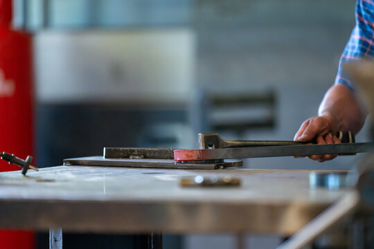Vue sur un forgeron chauffant un morceau de fer rougeoyant qu’il façonne au marteau pour lui donner la forme désirée dans son atelier traditionnel.