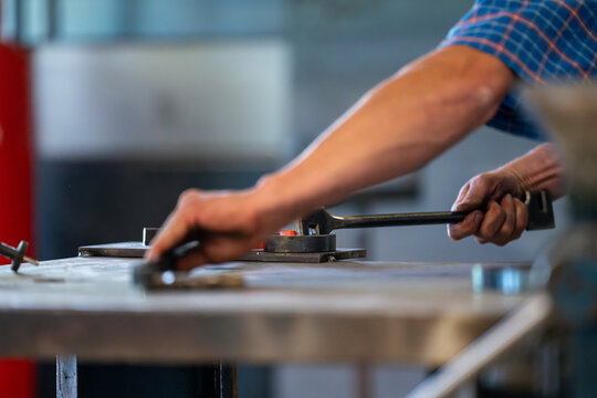Vue sur un forgeron chauffant un morceau de fer rougeoyant qu’il façonne au marteau pour lui donner la forme désirée dans son atelier traditionnel.