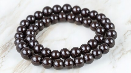 Obraz premium Elegant Round Dark Brown Beads Laid on a Light Marble Surface