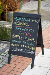 Aufsteller vor einem Cafe in Swinoujscie in Polen, mit einigen Angeboten an Frühstück, Kuchen und Getränken in deutscher und polnischer Sprache