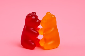 Gummy bears touching noses on a pink background, capturing a playful moment of affection between candy treats Generative AI