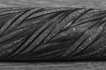 A spool of black thread on a wooden surface