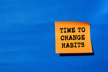 Time to change habits message written on orange paper on blue background. Conceptual time to change...