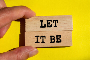 Let it be message written on wooden blocks on yellow background. Conceptual let it be symbol. Copy...