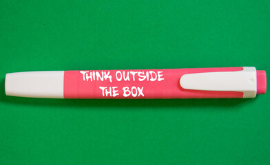 Think outside the box message written on pink marker pen on green background. Conceptual think...