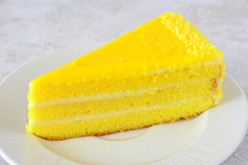 Delicious slice of layered lemon cake on a white plate close up