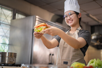 Young woman learning to cook, sandwiches and fresh vegetables placed on the table in a modern...