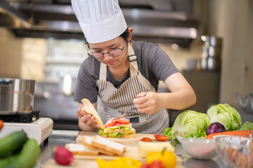 Young woman learning to cook, sandwiches and fresh vegetables placed on the table in a modern...