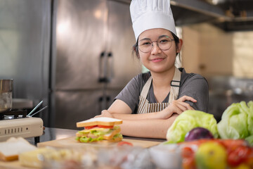 Young woman learning to cook, sandwiches and fresh vegetables placed on the table in a modern...